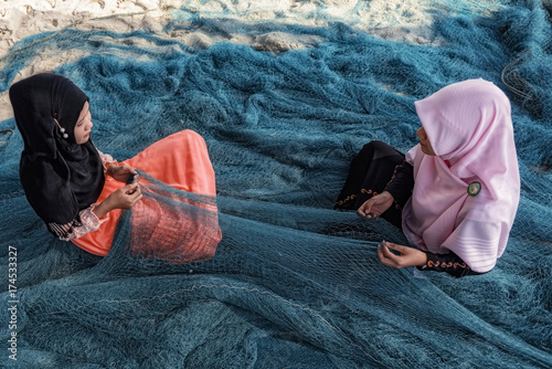muslim girl - fishermen are repairing fishing nets.Fishermen are cleaning fishing