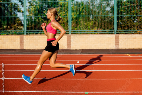 Side view beautiful young woman exercise jogging and running on athletic track on stadium