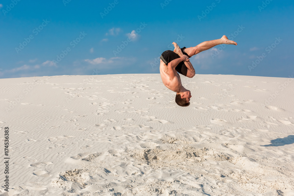 Portrait of young parkour man doing flip or somersault on the sand. Portrait of young parkour man doing flip or somersault on the sand.