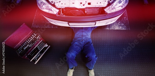 Foto Mechanic lying and working under car
