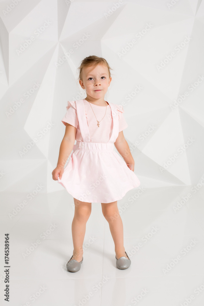 Beautiful little fashion model on white studio background. Portrait of cute girl posing in studio Beautiful little fashion model on white studio background. Portrait of cute girl posing in studio