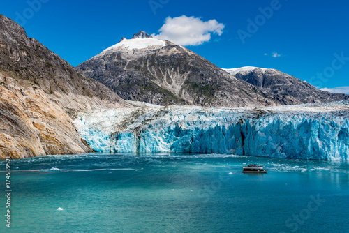 Wide angle view of glacier face with tourist boat and mountains