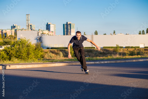 Happy young man rollerblading in city park at sunset. Outdoor  recreation  lifestyle  rollerblading