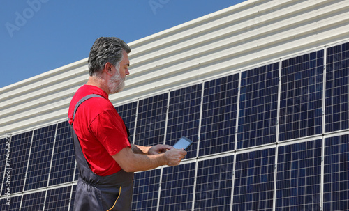 Engineer or worker calculate energy saving using tablet with solar panels in background