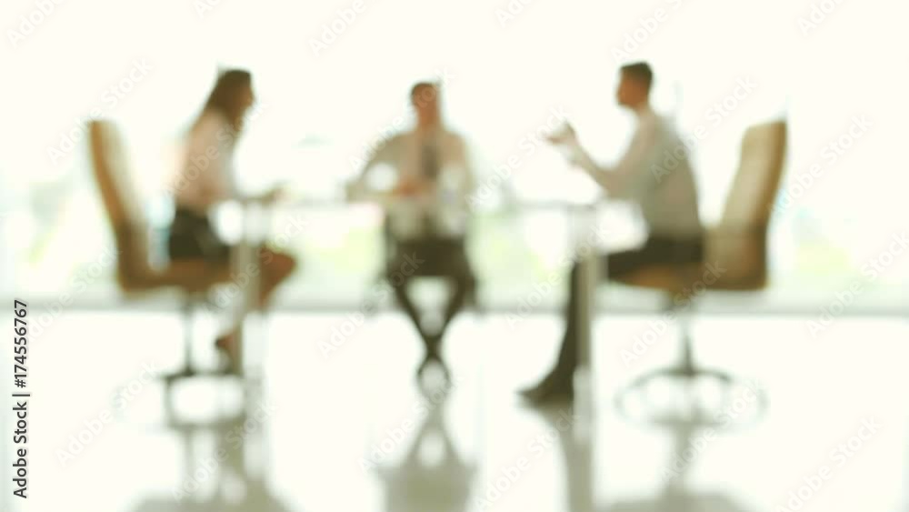 The three business partners discuss at the table. no focus