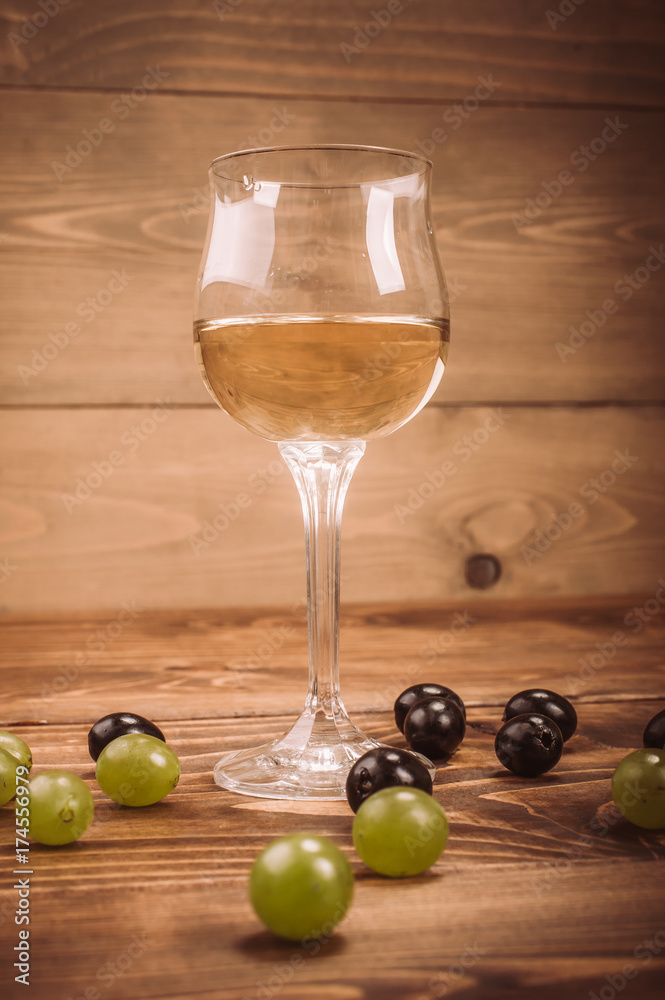 Glass of white wine and grapes on rustic wood table Glass of white wine and grapes on rustic wood table