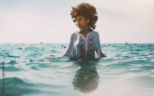 Obraz na plátně Attractive young black curly girl in traditional African chemise is standing up