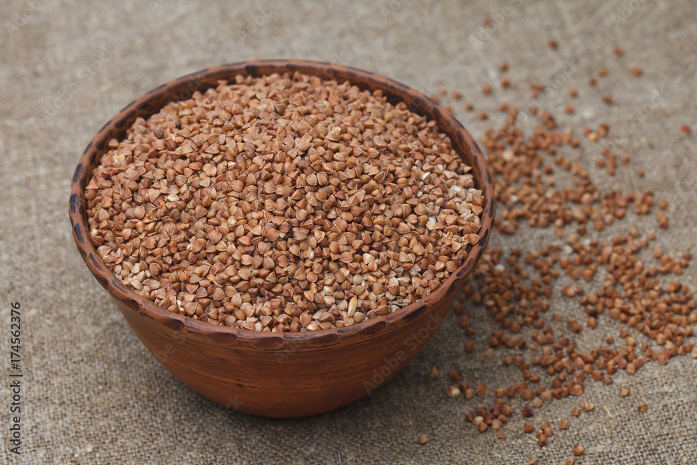 Healthy buckwheat groats in bowl on the burlap background closeup Healthy buckwheat groats in bowl on the burlap background closeup