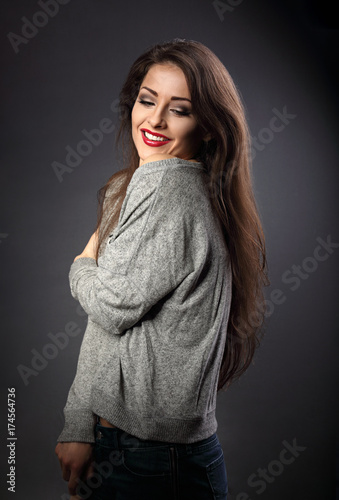 Happy beautiful young woman hugging herself with natural emotional enjoying face and toothy smiling on grey background. Closeup photo