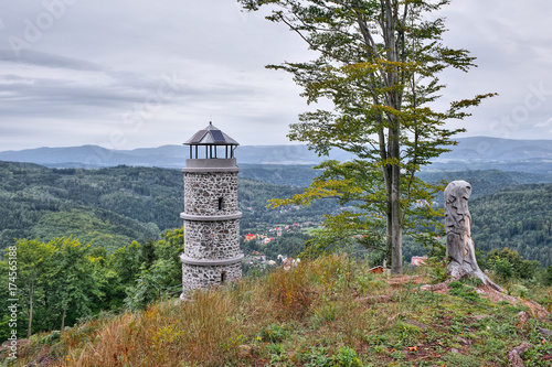 Big tree and stone lookout on top of Bucina hill with Ohre river valley and Ore mountains on background at beginning autumn czech photo