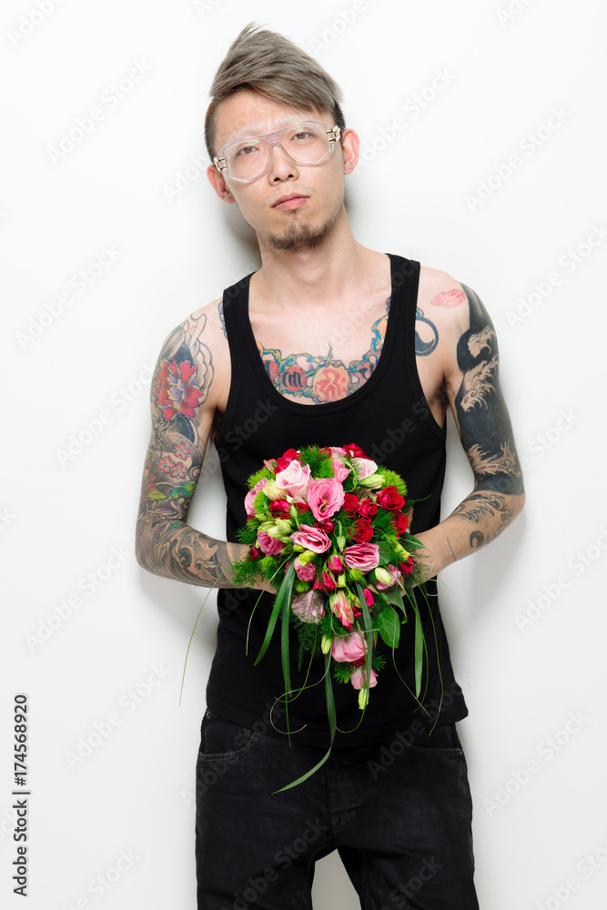 Portrait of man with tattoo holding a bunch of flower Portrait of man with tattoo holding a bunch of flower