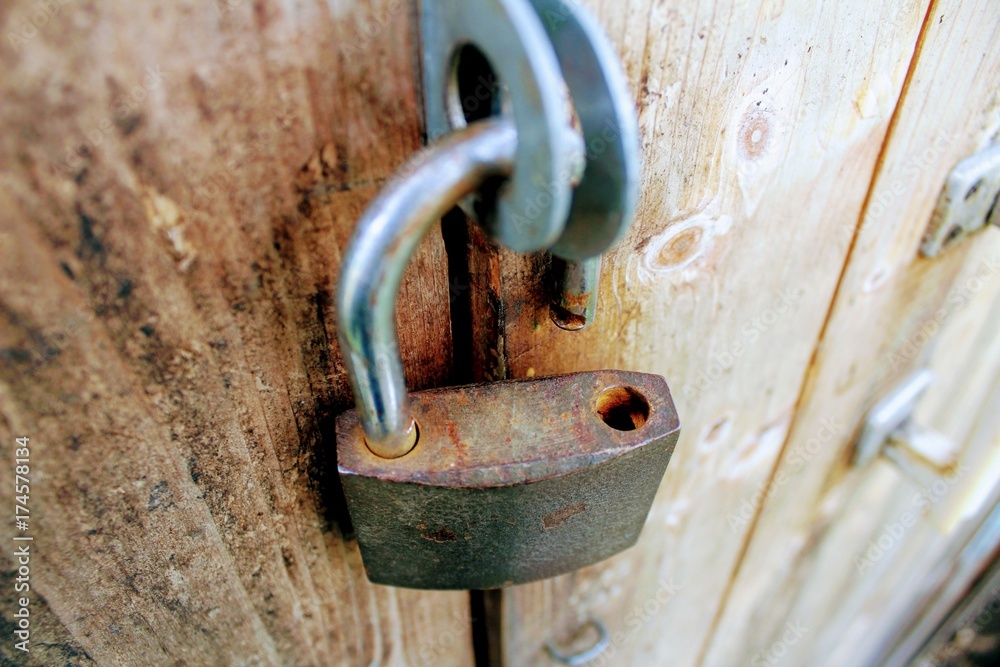 Open a padlock with traces of rust hanging on the door. Open a padlock with traces of rust hanging on the door.