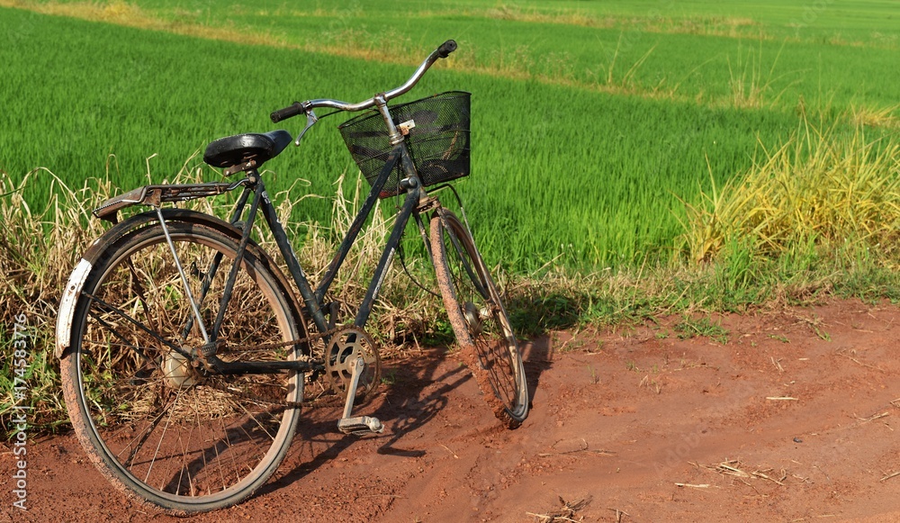 Naklejka premium old bicycle on soil and mud road in countryside 