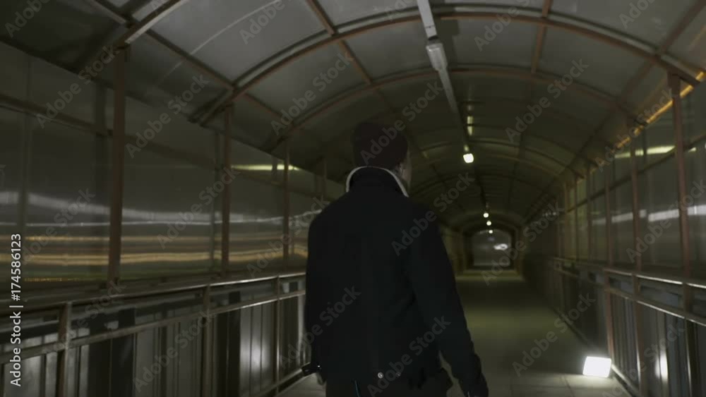 Guy walks alone on the overhead passage Guy walks alone on the overhead passage