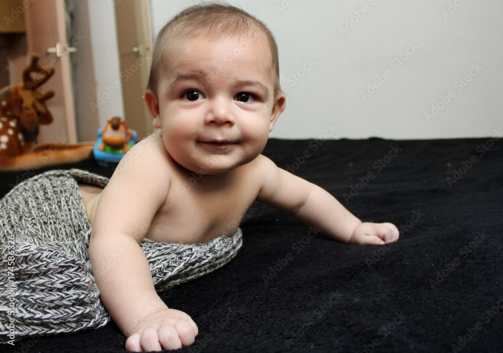 Fototapeta premium six month ols baby boy on black blanket profile face expresion