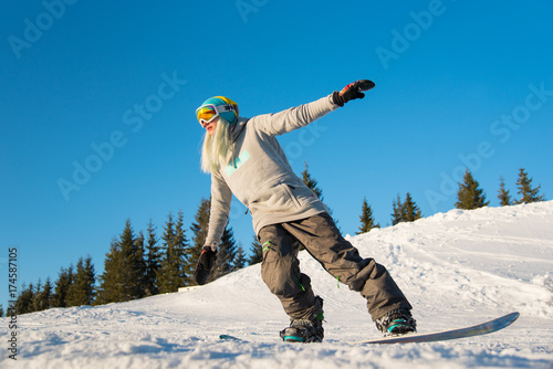 Full length shot of a blonde haired woman snowboarding in the mountains on a beautiful sunny winter day activity sports recreation youth concept