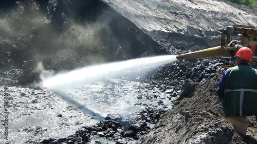 Worker in a helmet with special equipment blurs clay with water