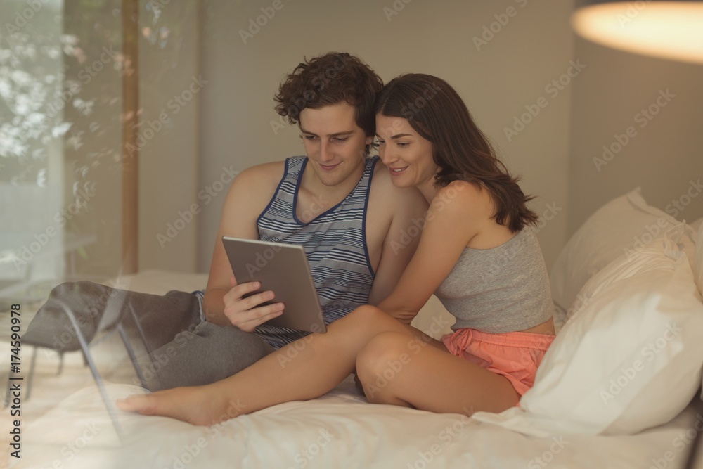 Smiling couple using digital tablet on bed Smiling couple using digital tablet on bed
