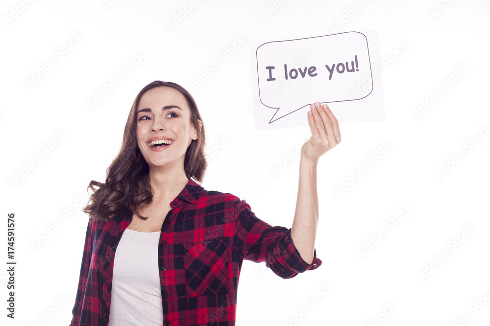 Young beautiful girl smiles and holds in her hands a white paper with an inscription i love you Young beautiful girl smiles and holds in her hands a white paper with an inscription i love you