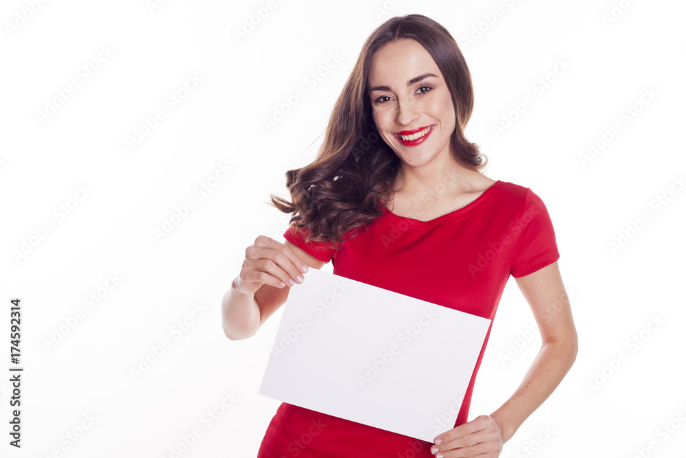 Beautiful smiling young brunette girl with clean skin in a red dress holding a white clean paper Beautiful smiling young brunette girl with clean skin in a red dress holding a white clean paper