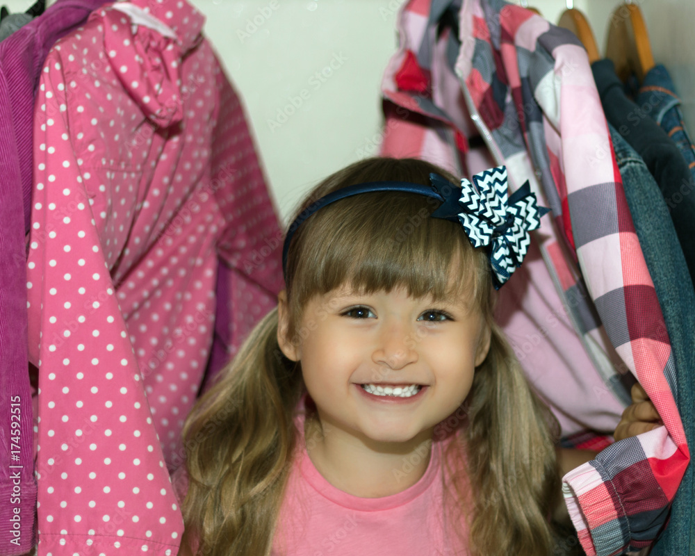 The European sweet little girl with blond hair brings wardrobe order, puts everything in its place, hides things in boxes. Wardrobe with women's, men's and child's clothing. Closet. Hiding. Disorder. The European sweet little girl with blond hair brings wardrobe order, puts everything in its place, hides things in boxes. Wardrobe with women's, men's and child's clothing. Closet. Hiding. Disorder.