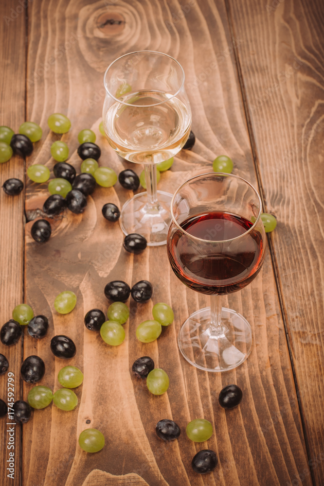 Red and white wine glasses and grape on wooden table Red and white wine glasses and grape on wooden table