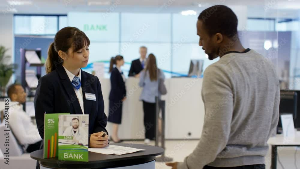 Bank worker on information desk giving help & advice to customers Bank worker on information desk giving help & advice to customers