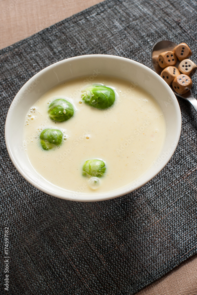 Smoked cheese and pumpkin puree soup with brussels sprouts. In bowl on grey tablecloth. Smoked cheese and pumpkin puree soup with brussels sprouts. In bowl on grey tablecloth.