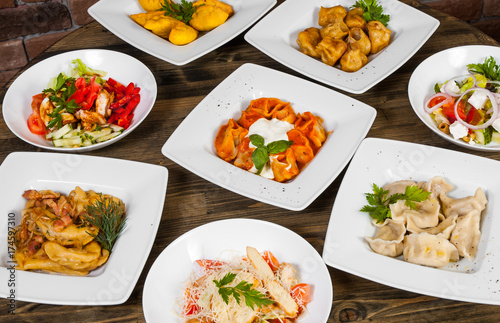 Set of different salads, dumplings and ravioli on a wooden table