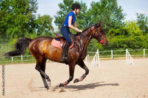 Female jockey galloping on horseback between jumps