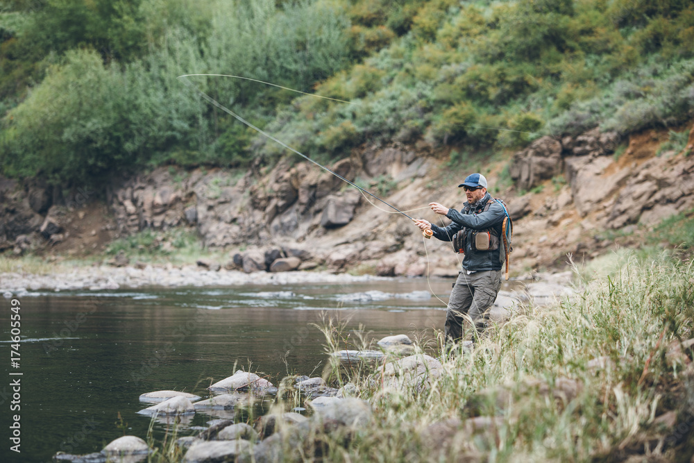 fly fisherman casting into a mountain river fly fisherman casting into a mountain river
