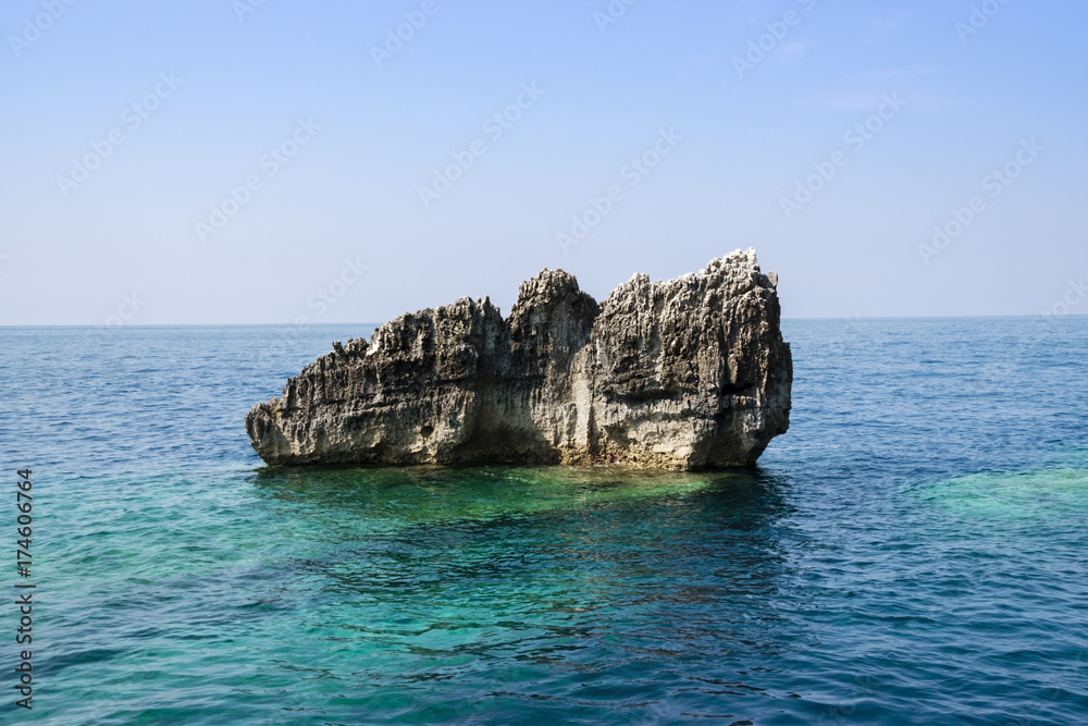 Naklejka premium Rock Formation In The Sea Against Clear Blue Sky