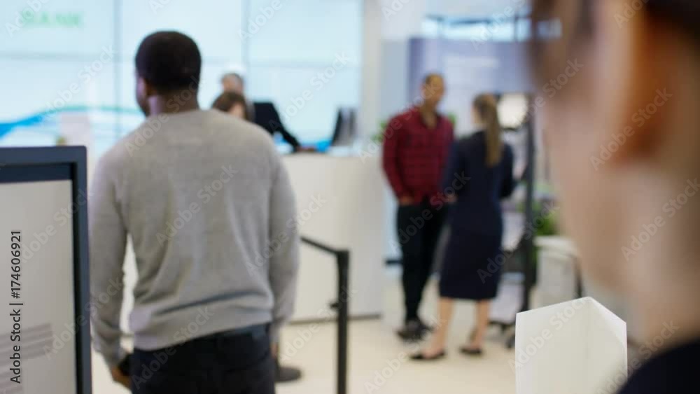 Worker at customer service desk assisting queue of customers in modern bank Worker at customer service desk assisting queue of customers in modern bank
