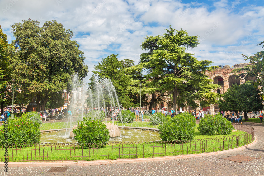 Sunny view of fountain in the park near famous landmark of Verona Arena or Amphitheater. Verona City in Italy. Sunny view of fountain in the park near famous landmark of Verona Arena or Amphitheater. Verona City in Italy.