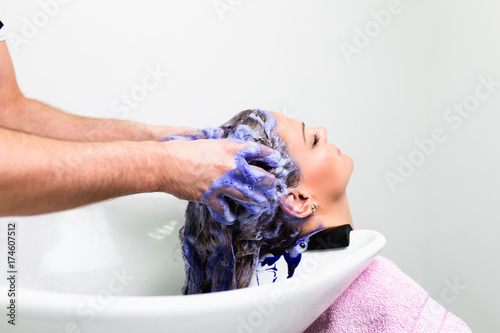 Hairdresser washing hair of a beautiful woman in hair salon. 