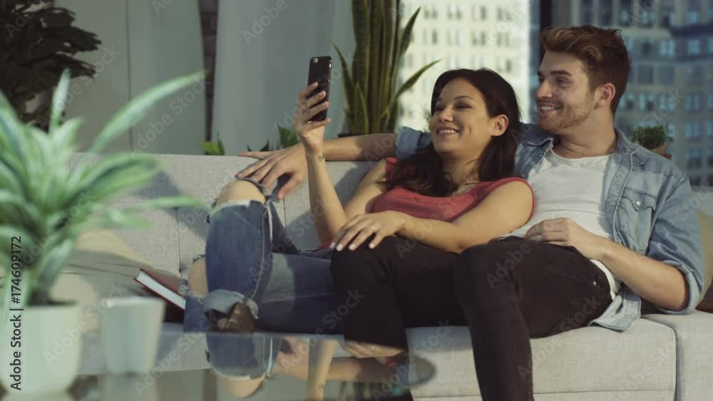 Affectionate couple relaxing at home & making video call on smartphone Affectionate couple relaxing at home & making video call on smartphone
