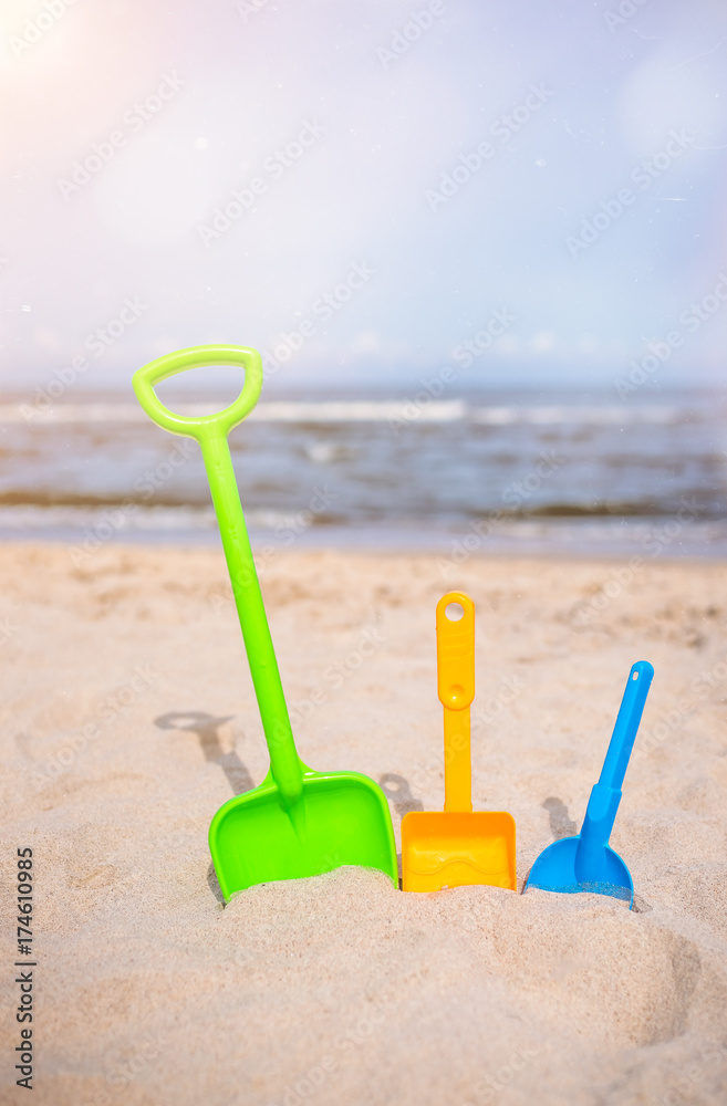 Three colorful toy shovels on the beach Three colorful toy shovels on the beach