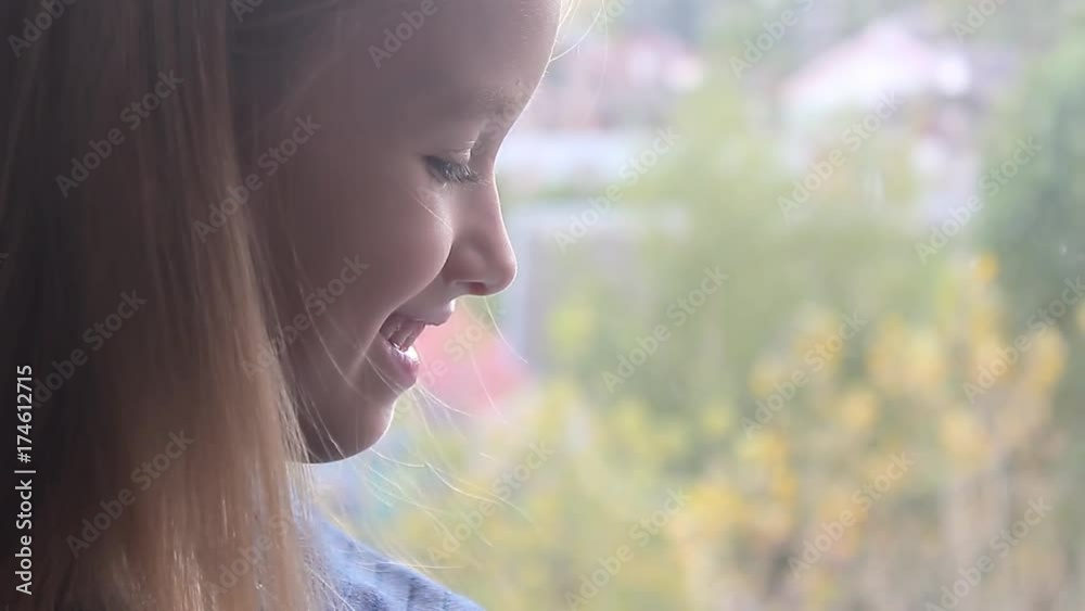 Cute child girl sitting by the window and reading a book in room at home. Cute child girl sitting by the window and reading a book in room at home.