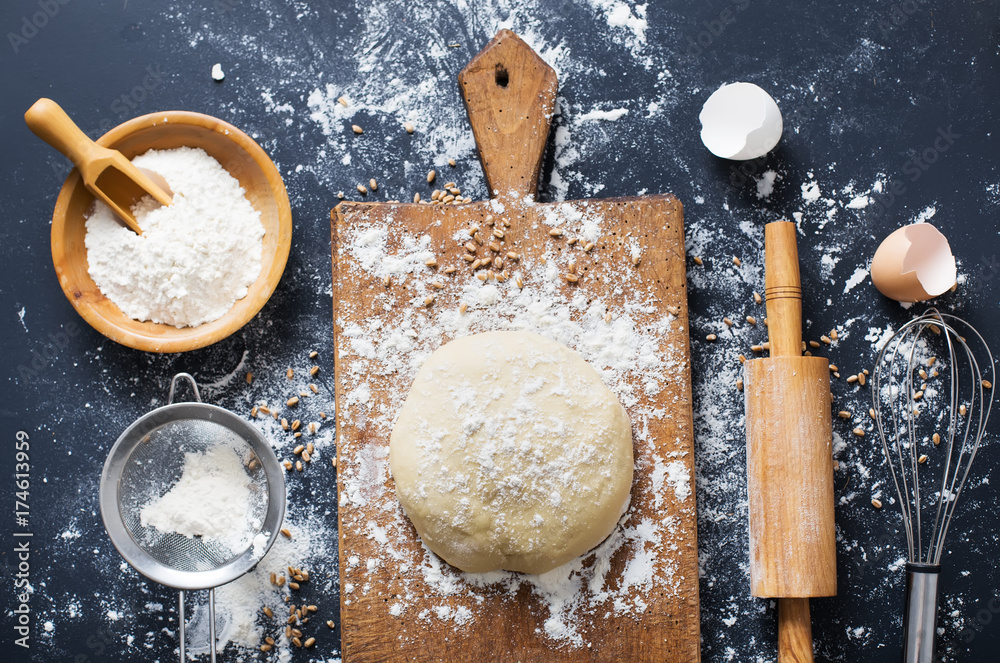 Baking ingredients. Bowl, eggs, flour, eggbeater, rolling pin and eggshells on black chalkboard from above. Baking ingredients. Bowl, eggs, flour, eggbeater, rolling pin and eggshells on black chalkboard from above.
