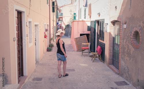 Italian summer holidays: woman tourist standing alone in a colorful alley narrow street in an old village in Tuscany, Italy © drimafilm