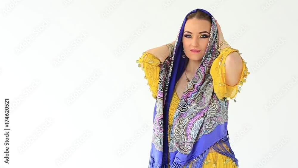 Beautiful arabian girl in black and yellow national clothing, covering her head in white studio backgraund . Slow motion Beautiful arabian girl in black and yellow national clothing, covering her head in white studio backgraund . Slow motion