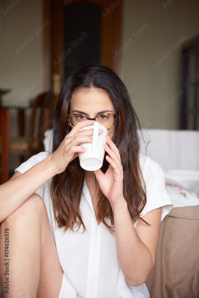 Woman drinking coffee while looking at camera Woman drinking coffee while looking at camera
