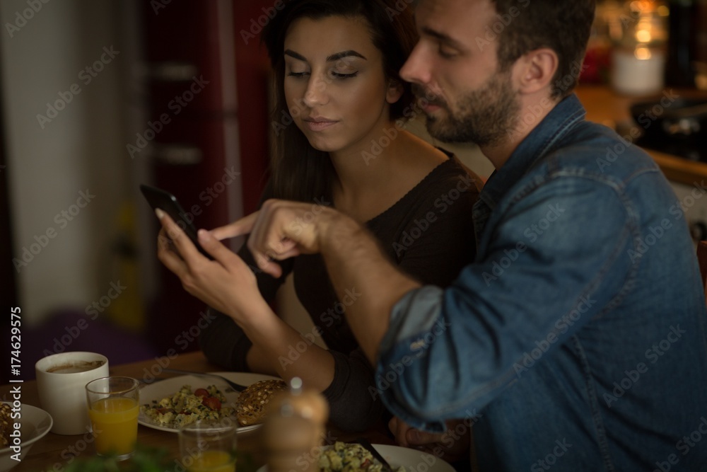 Couple using phone while having food