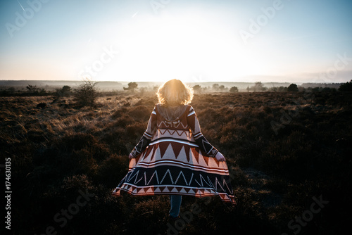 A woman walking in the heath in sunset light photo