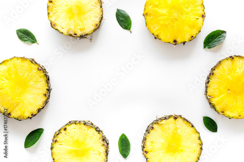 Pattern of round pinneapple slices and leaves on white background top view copyspace photo