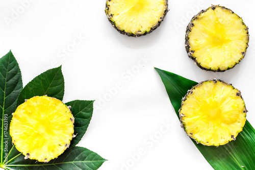 Tropical fruits concept. Pattern of pinneapple slices and leaves on white background top view copyspace photo