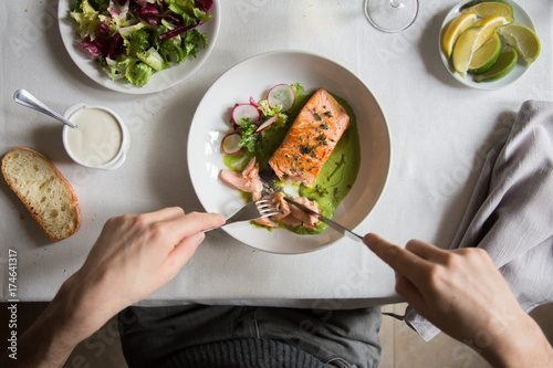 Man eating Salmon fillet with asparagus sauce and mixed salad photo