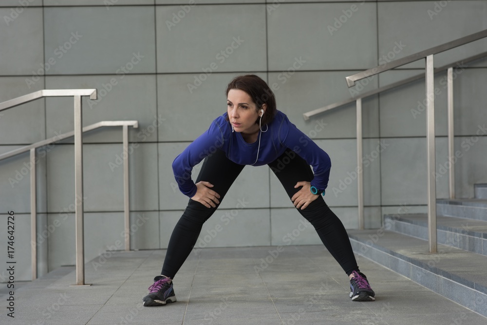 Woman performing stretching exercise on staircase Woman performing stretching exercise on staircase