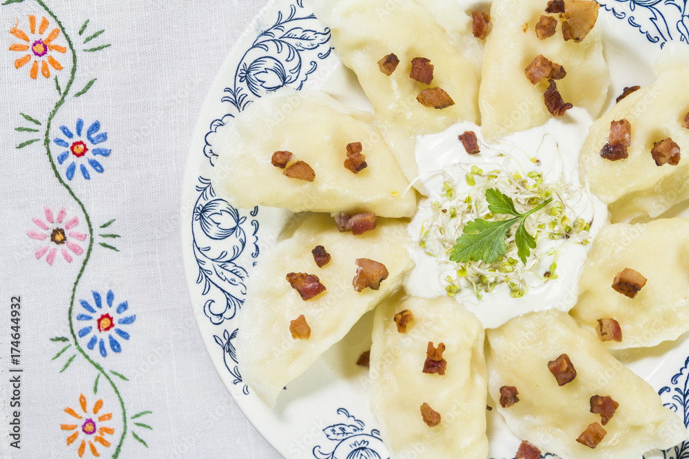 Cooked dumplings with cheese pork scratching and creme fraiche on wooden table. Cooked dumplings with cheese pork scratching and creme fraiche on wooden table.