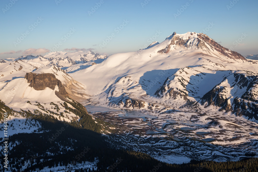 Fototapeta premium Aerial landscape view of Garibaldi Mountain and Lake still frozen during summer time after a cold winter. Taken near Squamish and Whistler, North of Vancouver, BC, Canada.